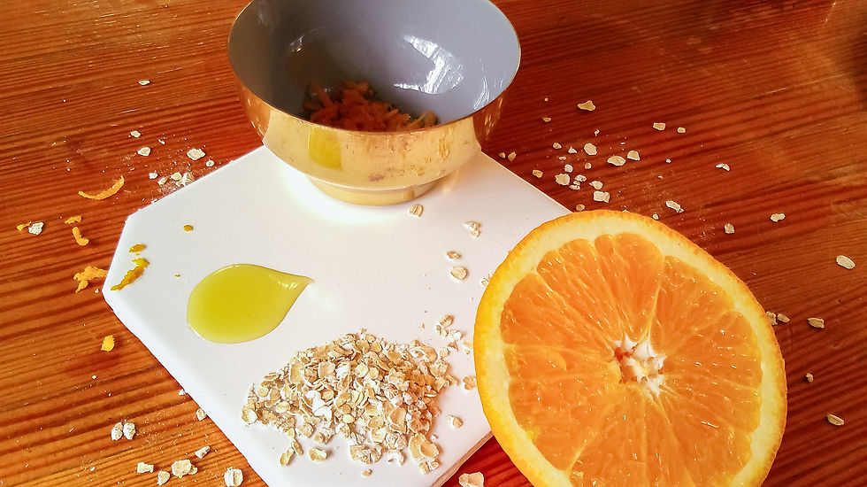 A half an orange, oats, olive oil, and orange zest in a bowl.