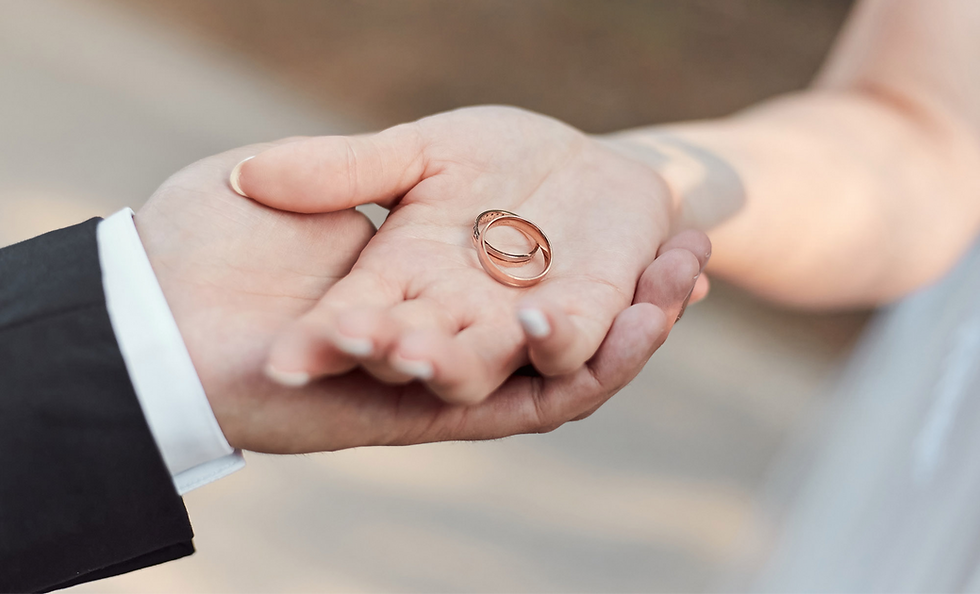 close up of the bride and groom holding their wedding rings in their hands