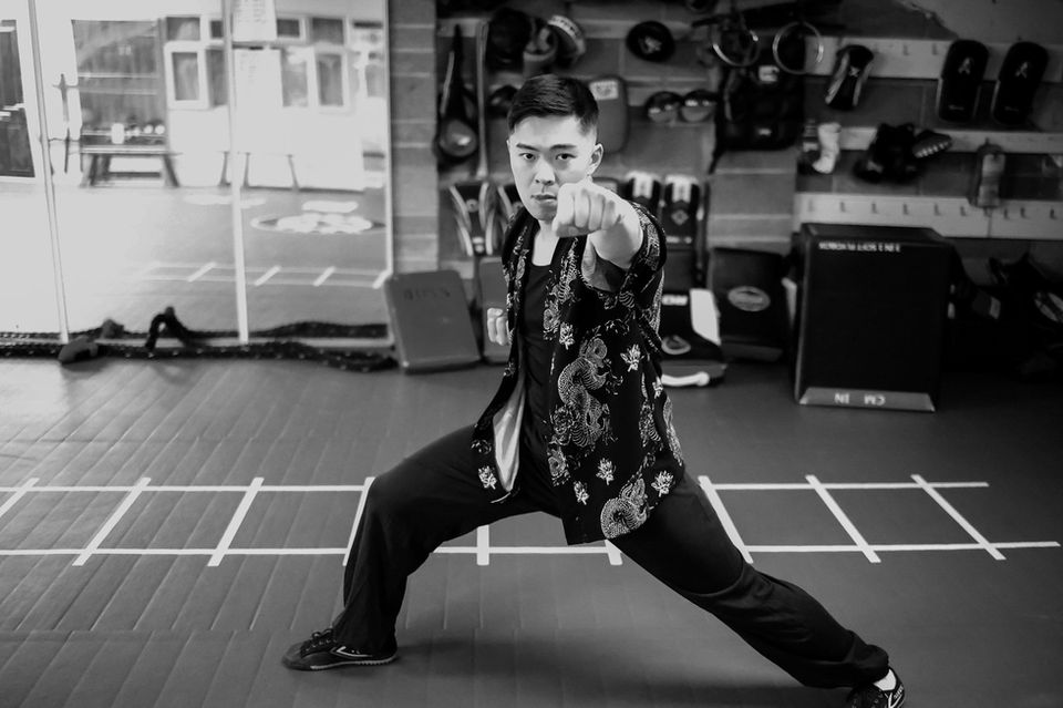 Man in martial arts stance wearing a patterned jacket