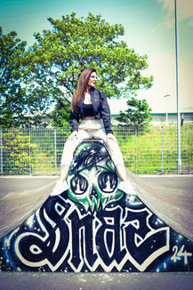 Woman in cream tracksuit pants and a black training top sitting on a ramp at a skatepark - urban fashion photoshoot in colour.