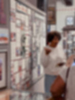 Curly-haired woman gestures before detailed museum informational wall panels.