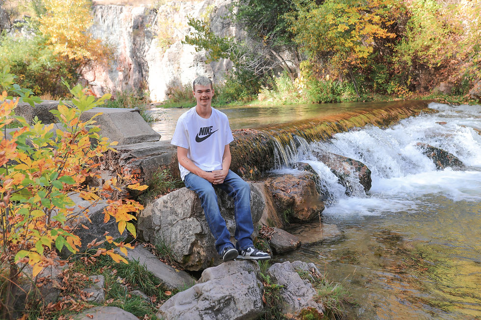 Eye-level view of a senior standing in a sunlit park with autumn leaves