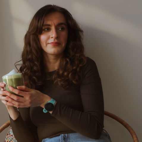Imogen holding a matcha latte in a minimal, natural setting, reflecting a calming hormone-supportive ritual