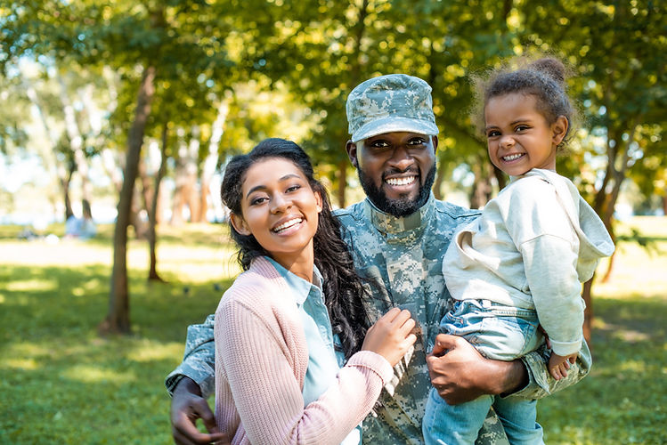 happy african american soldier in military uniform looking at camera with family in park.j