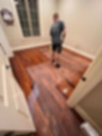 Dramatic transformation of hardwood floors with scratches and wear removed, revealing a smooth, professionally refinished surface.