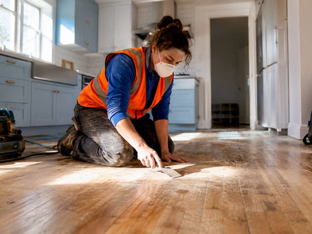 Worker inspecting stripped hardwood floor during prep