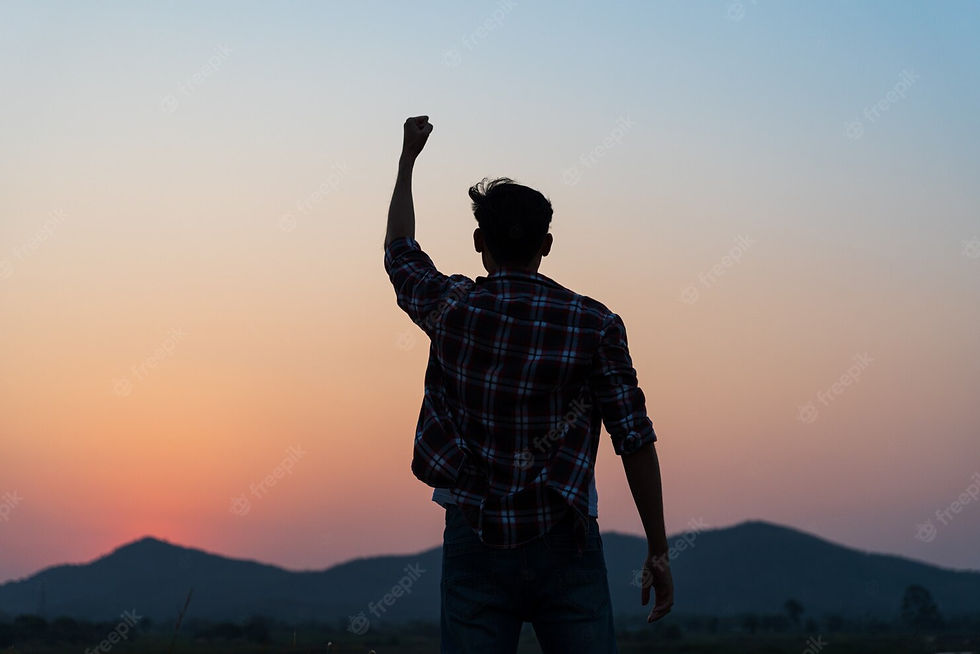 A boy celebrating by raising his fist while on top of a hill