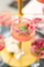 Coupe glass filled with pink cocktail and rose and rosemary garnish
