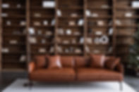 Leather sofa with cushions standing on living room with stylish interior design and collec