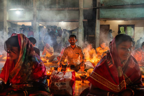 Hindu devotees offer their prayers, placing the oil lamps in front of them during the Rakher Upobash festival at Barodi, Narayanganj, Bangladesh on November 14, 2023. During this religious festival, known as Kartik Brati, Hindus fast and offer prayers by lighting oil lamps and candles. Throughout the country, thousands of devotees also visit temples to pray for good health. 