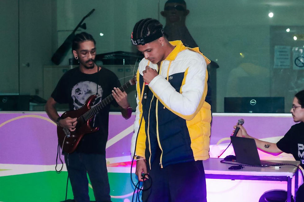 Nle Kira veste uma jaqueta azul e amarelo, está segurando o microfone enquanto canta em um show