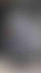 Treyvon em frente a um portão cinza, ele veste roupas pretas e tem o cabelo colorido