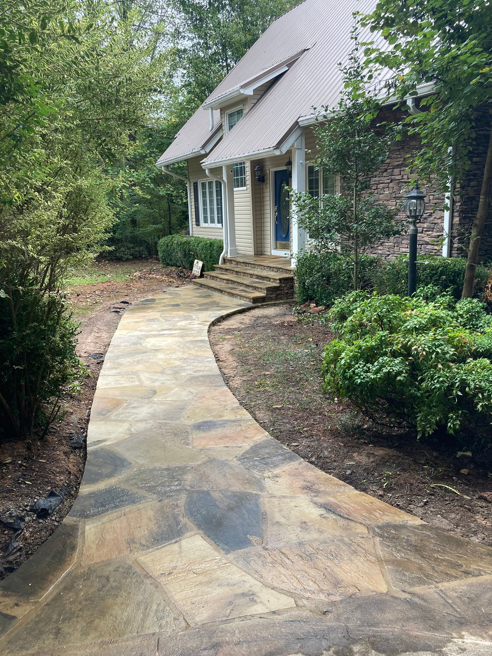 An elegant illuminated flagstone walkway with custom outdoor lighting, providing a safe and stylish path to your home’s entrance, enhancing curb appeal and nighttime landscape design.