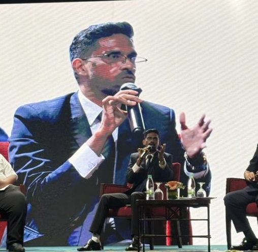 Gandhi Palanisamy speaking into a microphone during a public panel discussion