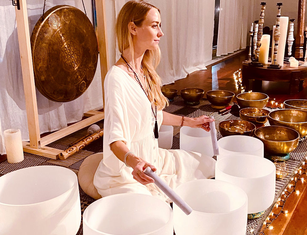 Viktoria from Seed of Life Healing playing crystal singing bowls, surrounded by Tibetan singing bowls and a gong during a sound healing session.