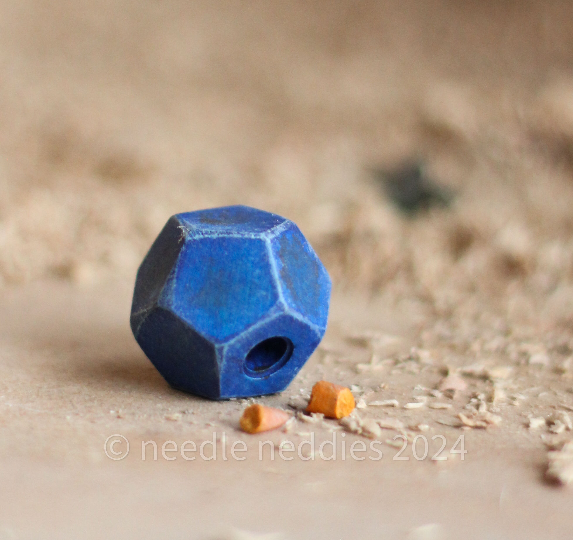 A dark blue treat ball, with pieces of carrot on the ground next to it.