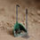 Thumbnail: A green poop scoop filled with manure and shavings. There is a fork sitting next to it.