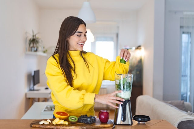 Young woman making detox smoothie at home