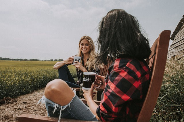 man and woman sitting outdoor on a field while drinking coffee