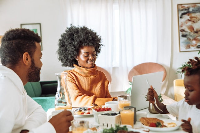 Happy family earing together while woman working on laptop