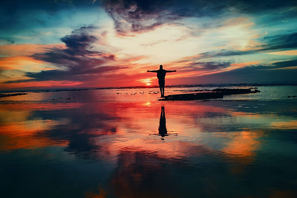 Person stretch arms in the middle of body of water during sunset
