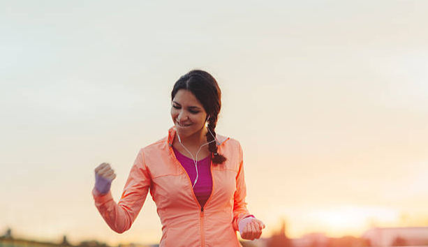 Female jogging in the city and finishing her training with her hand up in the air
