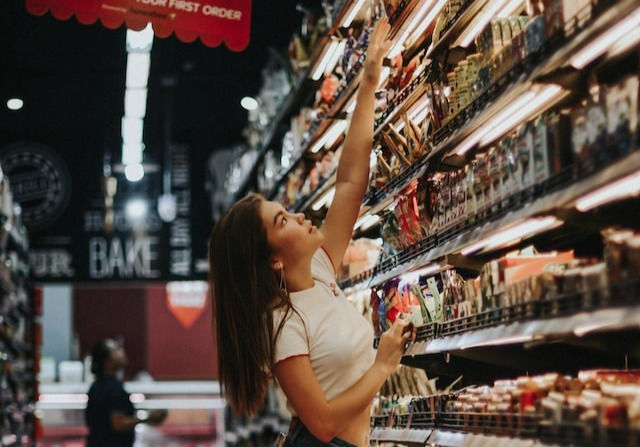 woman standing beside shelf reaching something