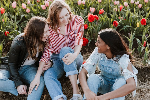 Three woman sitting near the flower.