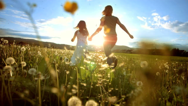 Mother and daughter running to the sun