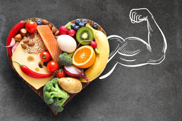 Healthy food on a heart-shaped wooden cutting board and a muscular arm