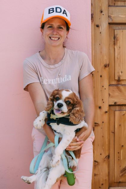 happy woman wearing cap carrying a dog
