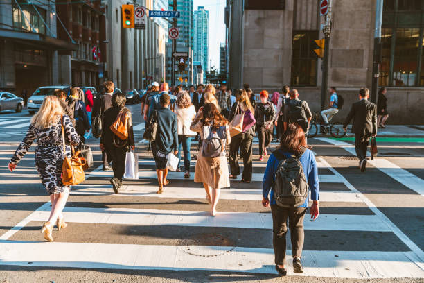 Crowd of unrecognisable people crossing street on traffic light zebra in the city.