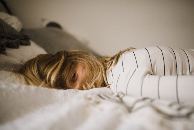 Woman face down in bed feeling burned out