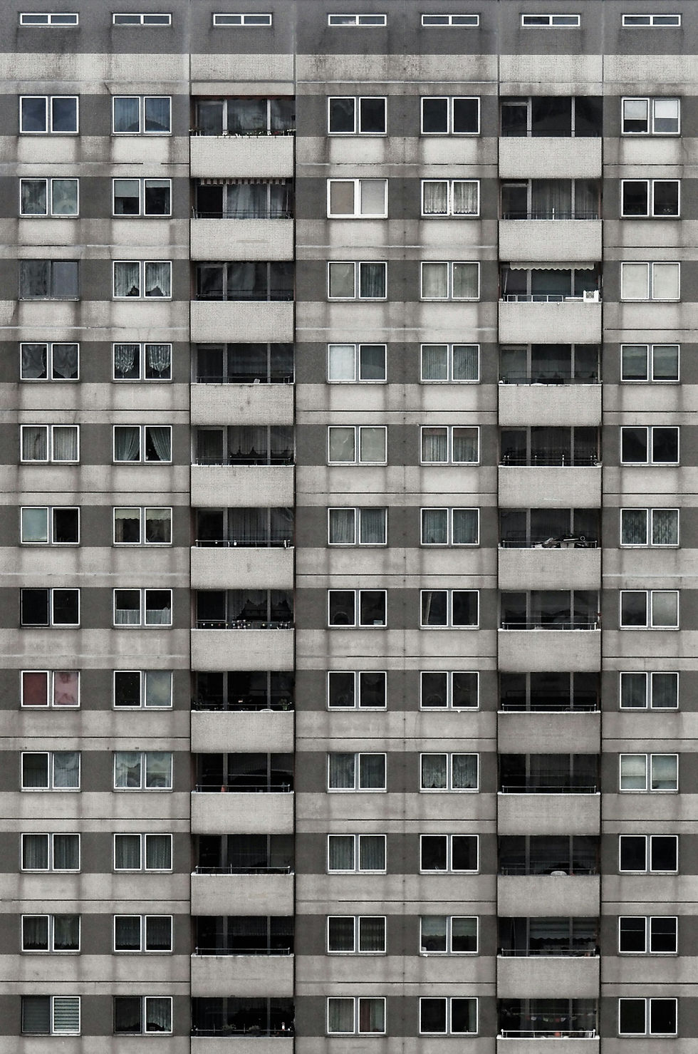 Grey concrete apartment facade in Berlin with rows of identical, separate windows