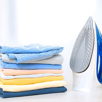 Stack of colorful cotton clothes and iron.Household laundry ironing..jpg