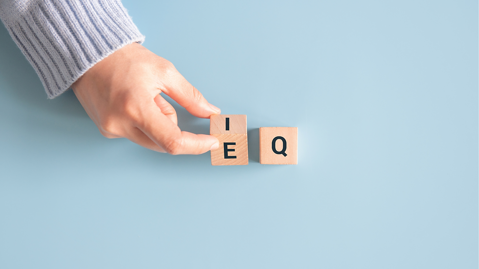 Hand arranging wooden blocks labeled I, E, Q on a light blue background. Emotional intelligence.