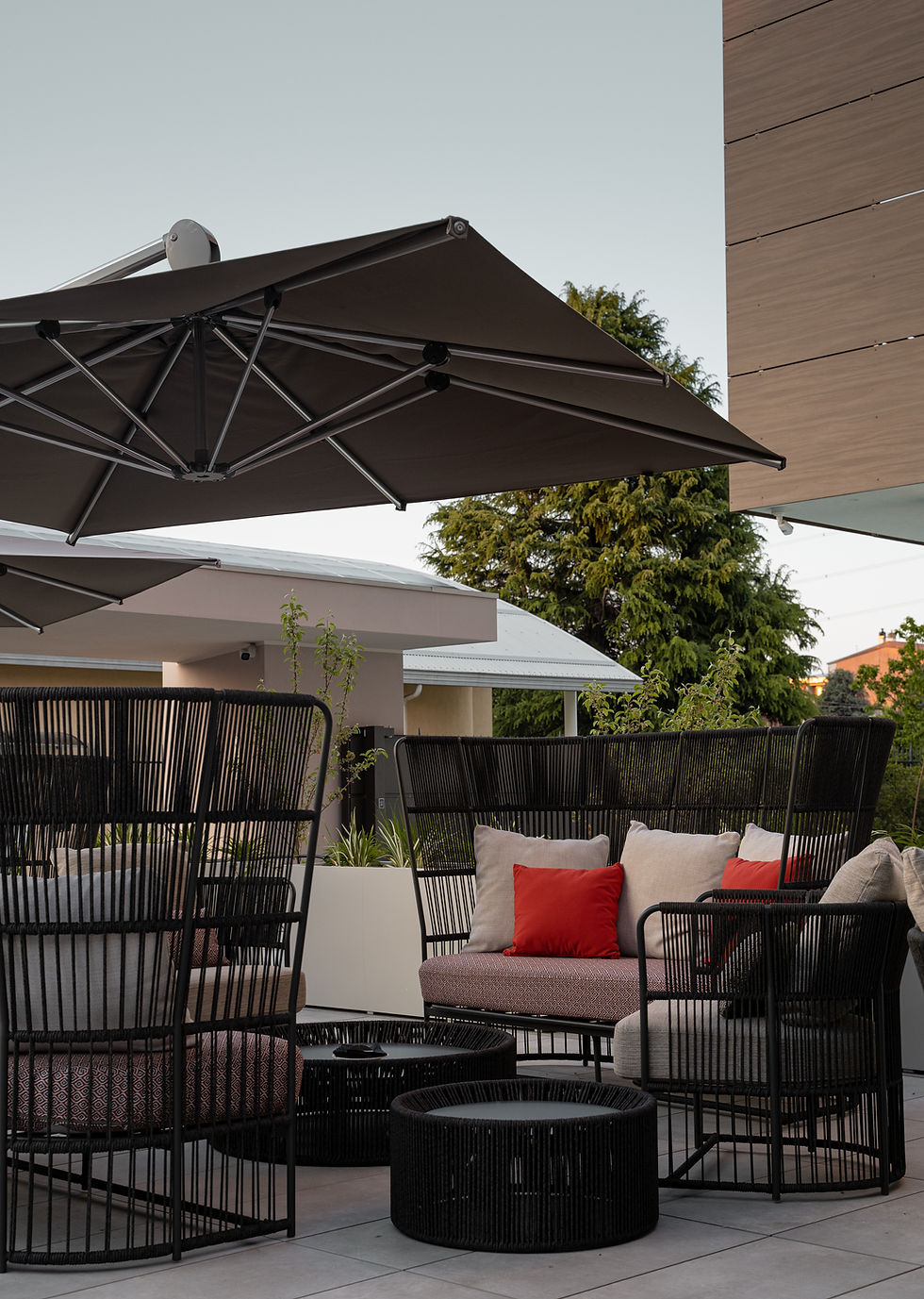 Lounge esterno di Elitis House con divani in corda nera e ombrelloni, area aperitivo all'aperto in Brianza