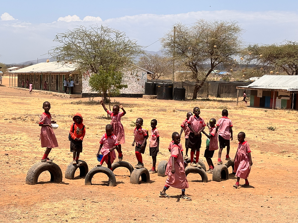 A group of joyful school children playing outdoors at the Memusi Foundation school in Magadi, Kenya, showcasing the importance of physical activity and play in their education.