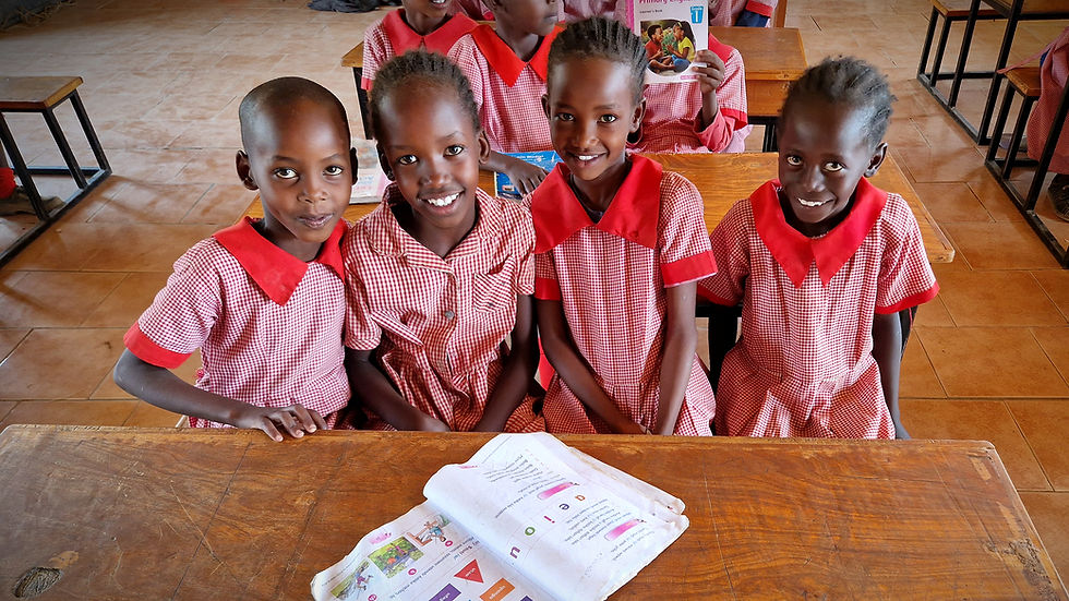 A joyful group of primary school students sitting behind their desks and smiling at the camera in a Memusi Foundation classro