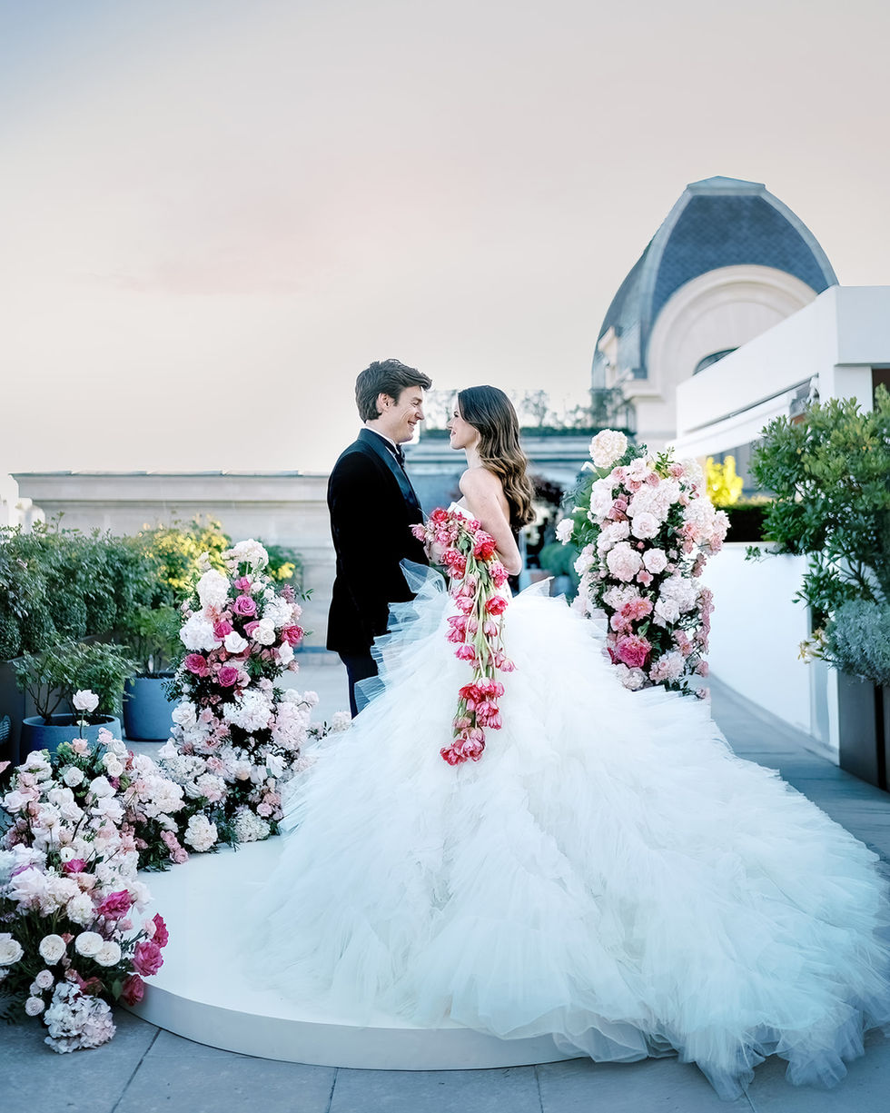 Smiling newlyweds on a terrace, dome of a Parisian hotel, cascade of tulips
