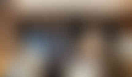 Four panelists engaged in a panel conversation while seated by a large stone fireplace.