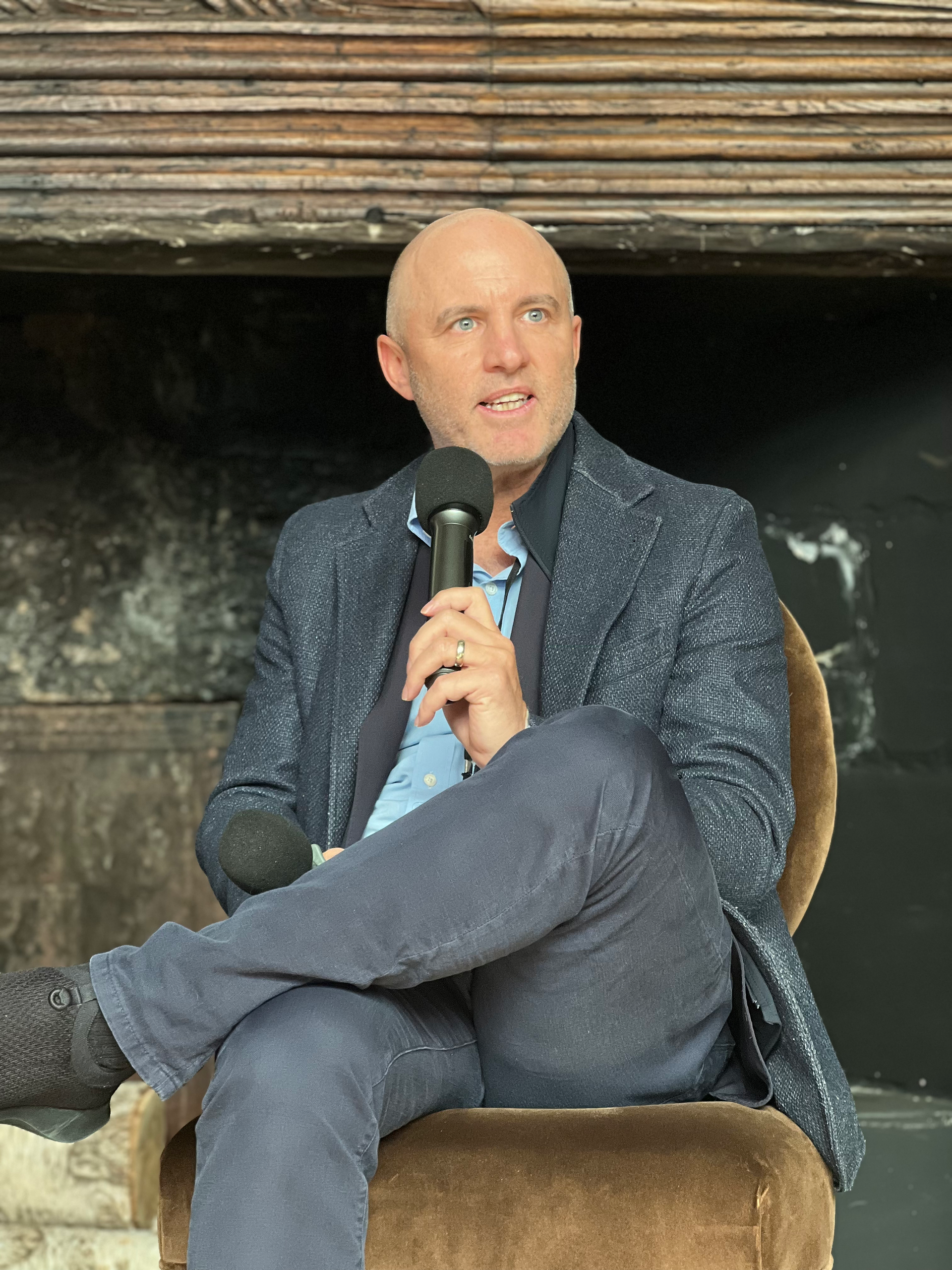 Male panelist speaking from stage at AI & Impact event