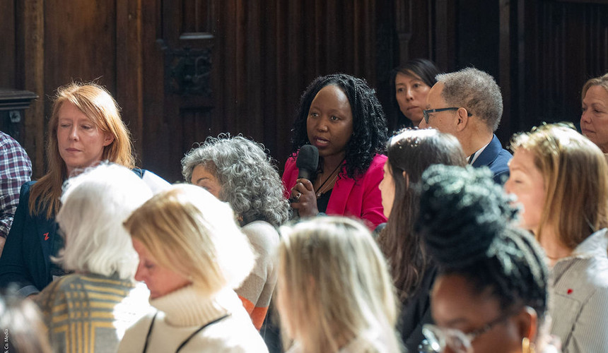 Woman in audience holds microphone asking a question to the presenters.
