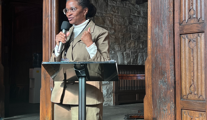 Speaker presenting at a podium near a barn door entrance at Foundation House.