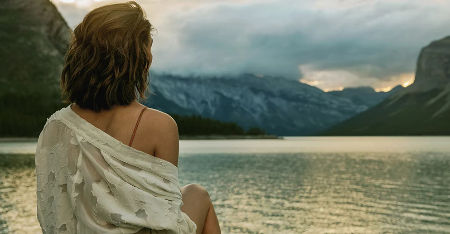 An eye-level view of a woman sitting by a lake somewhere in Alberta, Canada