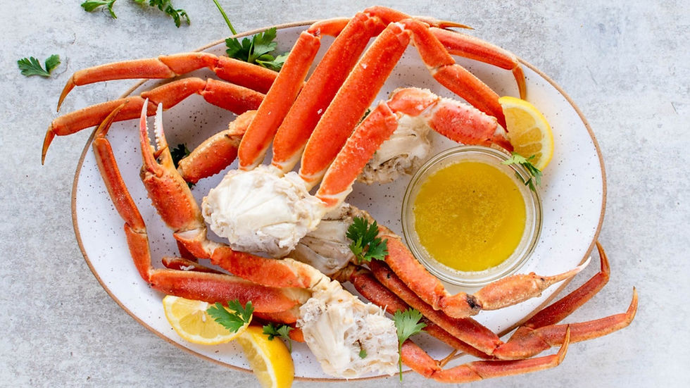 Plate of bright red crab legs with melted butter, lemon wedges and parsley on a stone surface, ready to eat.