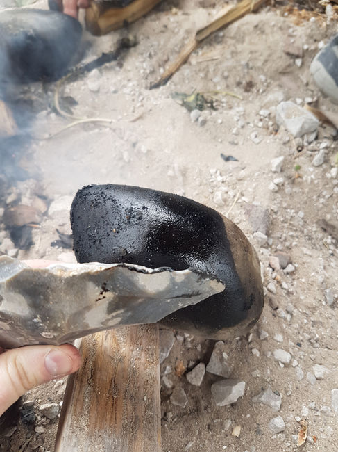 Cobble showing birch tar residue from experimental hearth production, with Peter Hommel. Photo by Rebecca Wragg Sykes.
