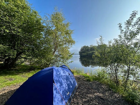 Solo camping tent pitched on the grassy shores of Lake Windermere