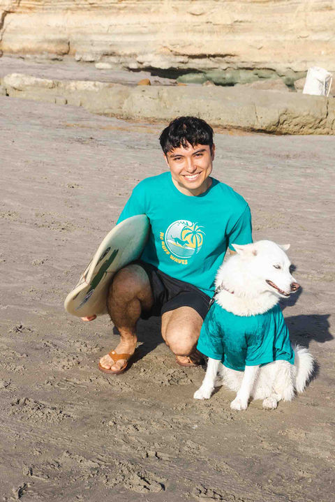 A man going surfing with his dog in matching shirts