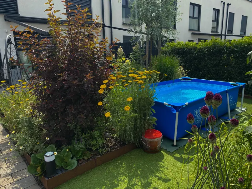 Üppig bepflanztes Beet mit Begrenzung aus Cortenstahl und rechteckigem Aufstellpool